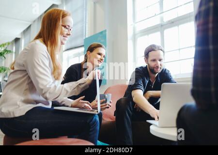 Businesspeople using laptop together in creative office Stock Photo