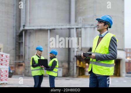 Male worker using digital tablet while looking away at factory Stock Photo