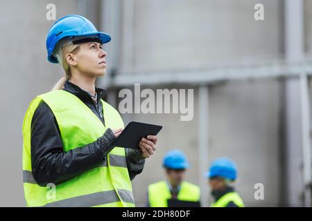Female worker using digital tablet while looking away at factory Stock Photo