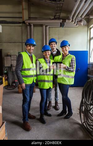 Full length portrait of confident manual workers using digital tablet in factory Stock Photo