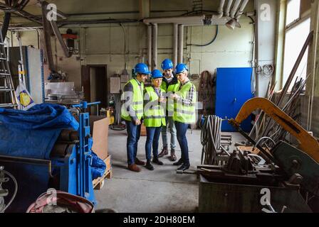 Full length of male and female workers using digital tablet in factory Stock Photo