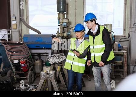 Manual workers with digital tablet discussing in factory Stock Photo