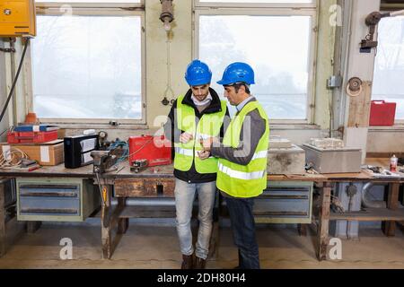 Manual workers repairing machine part in factory Stock Photo