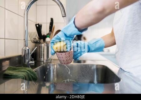 Midsection of woman washing glass with scouring pad at sink Stock Photo