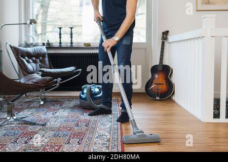Low section of man vacuuming floor at home Stock Photo
