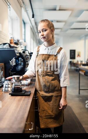 Portrait of confident female barista standing at counter in coffee shop Stock Photo