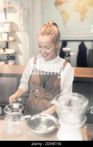 Smiling female barista preparing coffee at counter Stock Photo