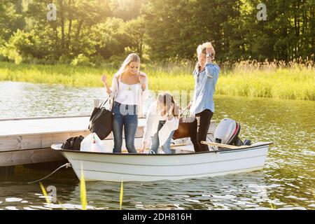 Happy friends with luggage enjoying in boat on lake