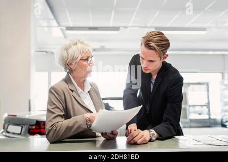 Two sales colleagues discussing documents at car dealership Stock Photo