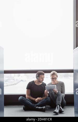 Business colleagues using digital tablet while sitting by window in office Stock Photo