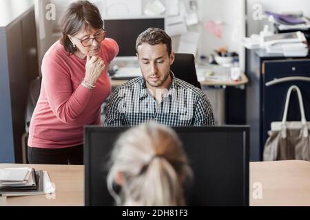 Colleagues using computer at desk in office Stock Photo