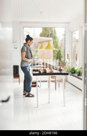 Full length side view of female architect working at table in home office Stock Photo