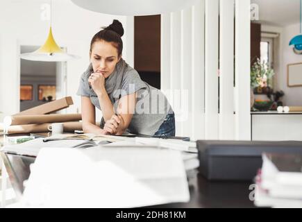 Thoughtful female architect leaning on table at home office Stock Photo