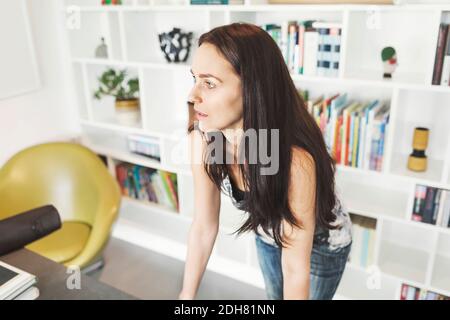 Thoughtful female architect leaning on table at home office Stock Photo