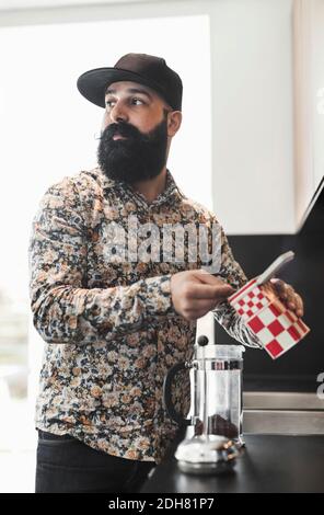 Man looking away while preparing coffee in kitchen Stock Photo