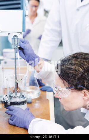 Side view of female scientist using pipette in laboratory Stock Photo