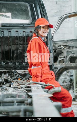 portrait of a female technician with broken car in the garage Stock Photo