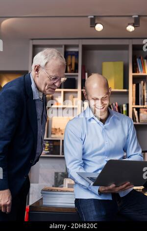 Happy businessmen using laptop together in office Stock Photo