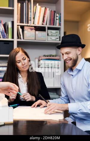 Male and female architects working on blueprint at desk in office Stock Photo
