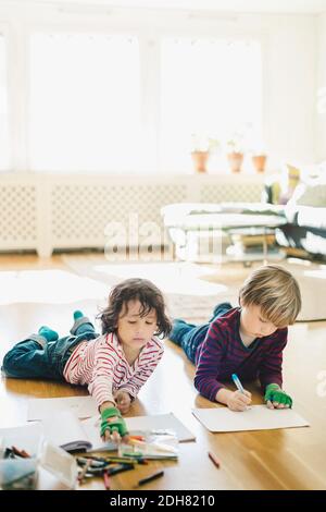 Friends coloring in books while lying on floor at home Stock Photo