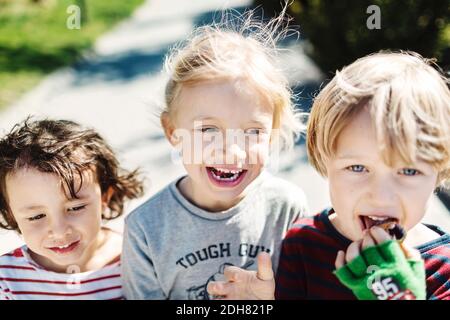 Portrait of happy boy eating ice cream while walking with friends at yard Stock Photo