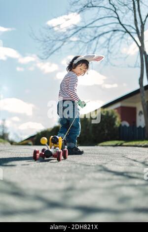 Full length of boy pulling toy car on footpath at yard Stock Photo