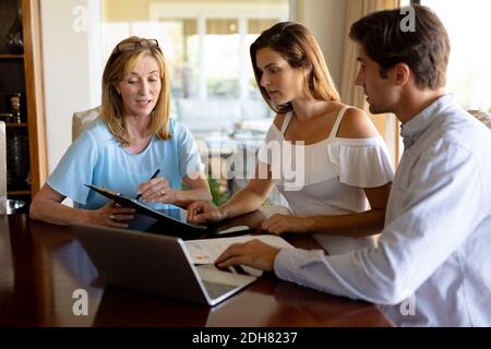 Young couple discussing with a financial adviser at home Stock Photo