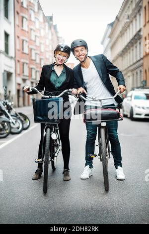 Portrait of happy business people with bicycles standing on city street Stock Photo