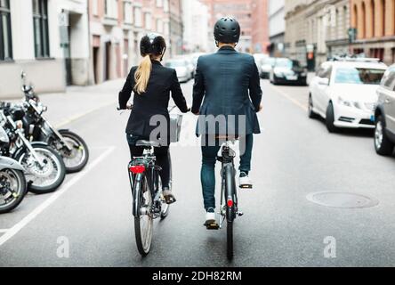 Rear view of business people riding bicycles on street Stock Photo
