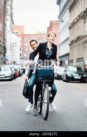 Happy business people riding bicycle on city street Stock Photo