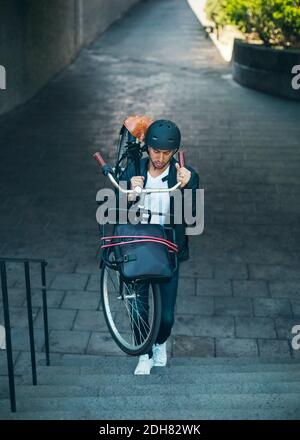 Businessman carrying bicycle while moving up steps Stock Photo