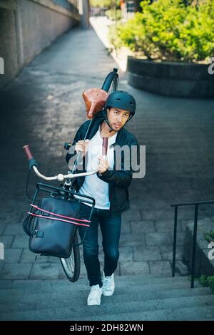 Businessman carrying bicycle while moving up steps Stock Photo