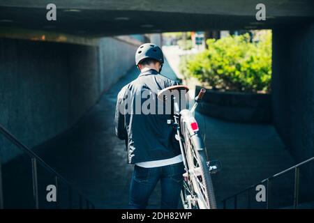 Rear view of businessman carrying bicycle while moving down steps Stock Photo