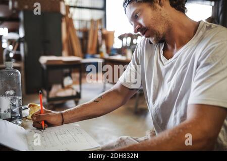 Carpenter using mobile phone while reading document in workshop Stock Photo