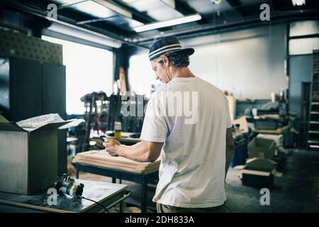 Carpenter using mobile phone in workshop Stock Photo
