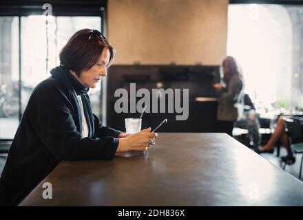 Side view of senior woman using smart phone at cafe Stock Photo