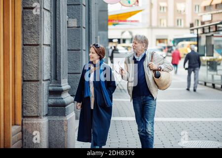 Senior couple looking at store window while walking on city street Stock Photo