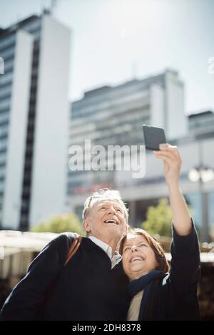 Senior couple taking selfie through smart phone in city Stock Photo