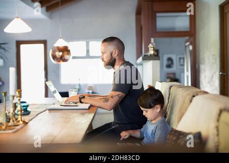 Side view of father and son using technologies at dining table Stock Photo