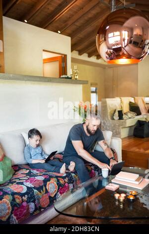 Father and son using digital tablets in living room at home Stock Photo