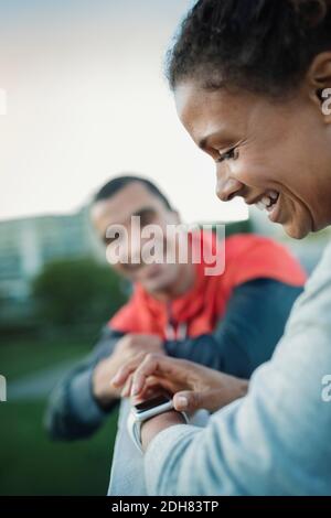 Smiling woman using smart watch while standing by friend Stock Photo