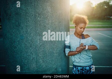 Woman using smart watch while standing by column Stock Photo