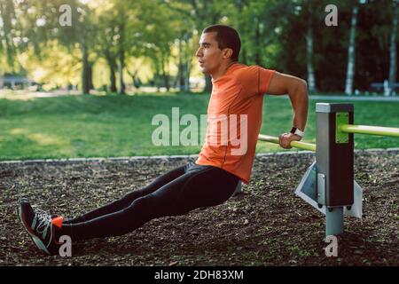 Man doing push-ups on railing at park Stock Photo