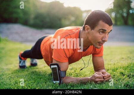 Man doing plank exercise on grassy field at park Stock Photo