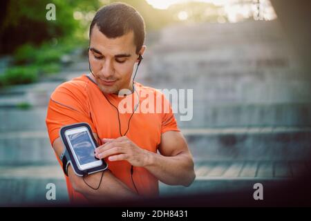 Man using smart phone armband while standing at steps Stock Photo