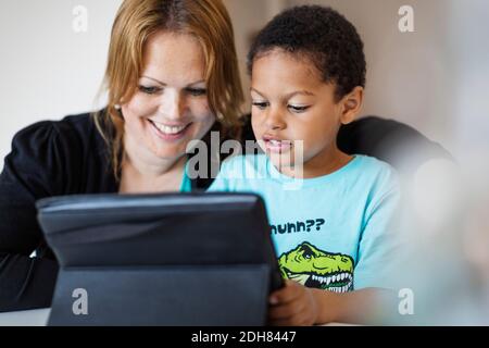 Happy mother using digital tablet with son at home Stock Photo