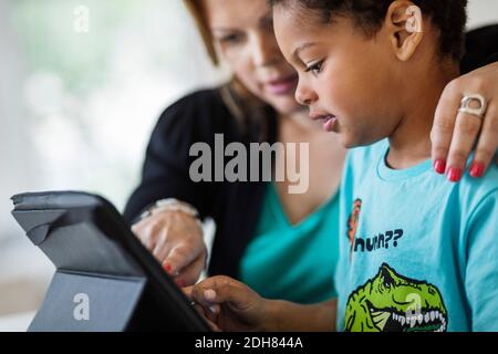 Mother assisting son in using digital tablet at home Stock Photo