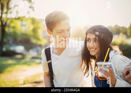 Happy teenage boy looking at friends holding disposable glass outdoors Stock Photo