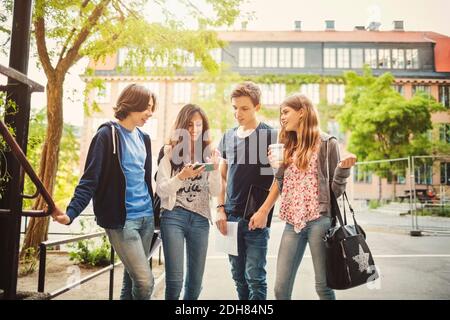 Happy teenagers using smart phone on street Stock Photo
