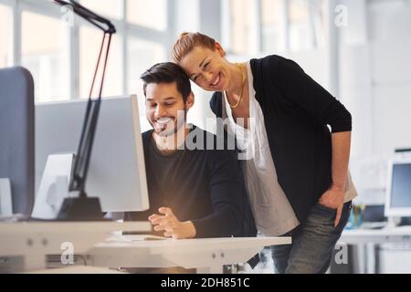 Happy businesswoman with male colleague using computer in office Stock Photo